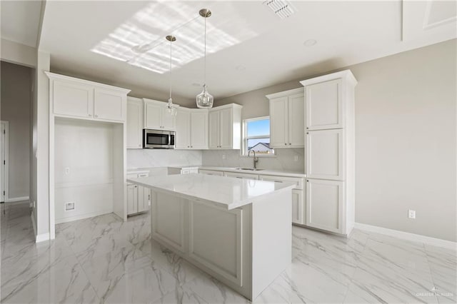 2005 Lime St, San Juan, TX 78589 - kitchen with stainless steel microwave, light marble finish floors, a center island, and white cabinetry