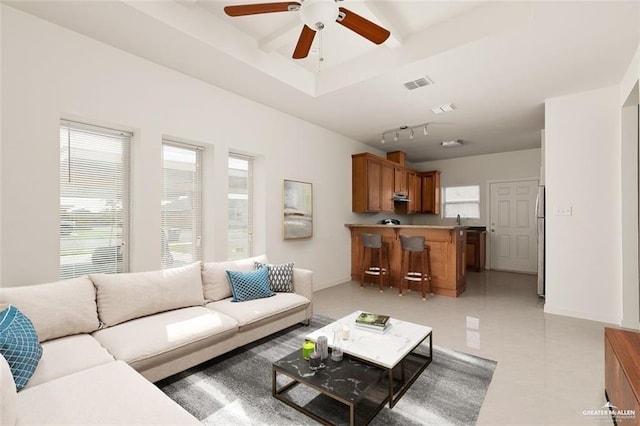 living area featuring a tray ceiling, visible vents, ceiling fan, and baseboards