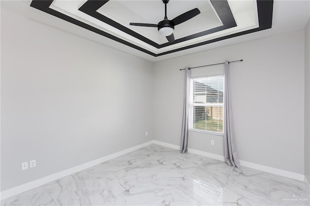 unfurnished room with ceiling fan and a tray ceiling