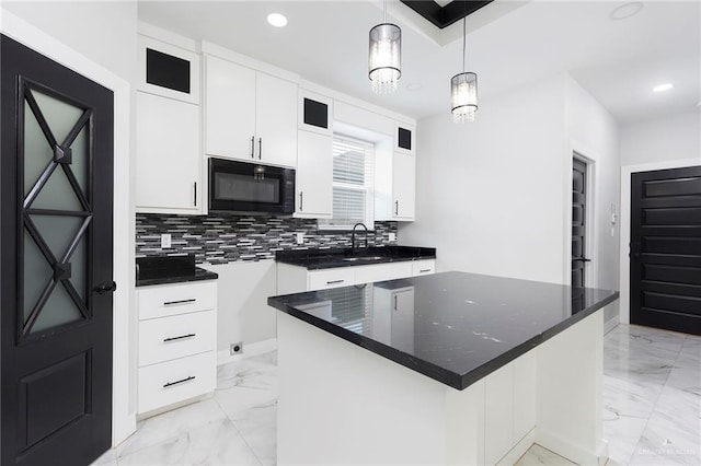 kitchen featuring decorative backsplash, a kitchen island, sink, white cabinetry, and hanging light fixtures