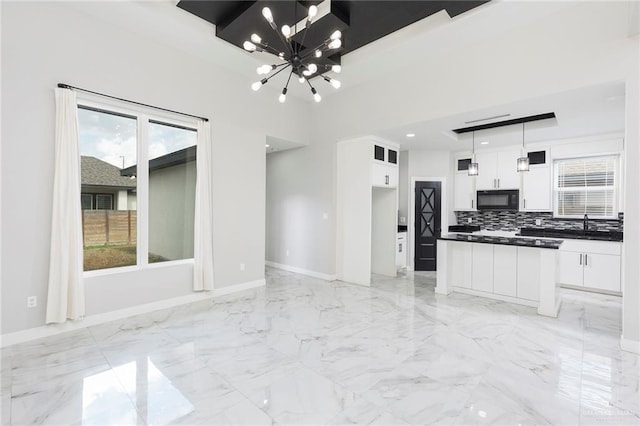 kitchen featuring decorative light fixtures, white cabinetry, a wealth of natural light, and a notable chandelier