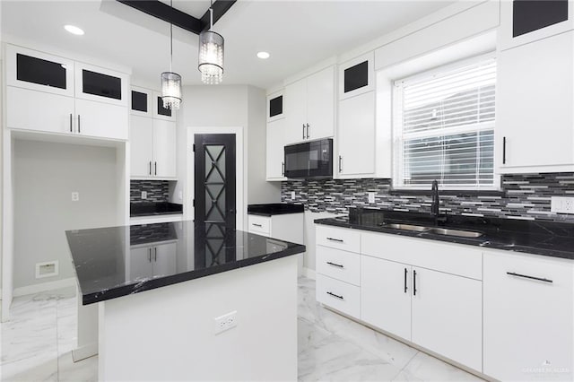 kitchen with tasteful backsplash, sink, pendant lighting, white cabinetry, and a kitchen island