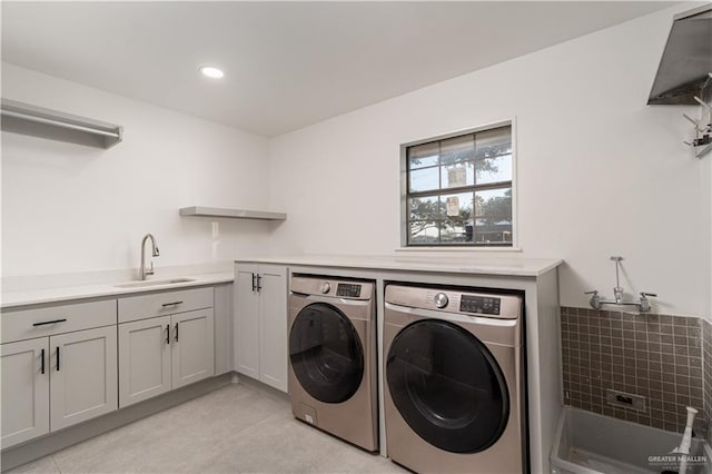 washroom with cabinets, sink, light tile patterned floors, and washer and dryer