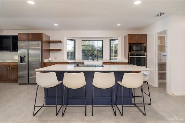 kitchen featuring a kitchen breakfast bar, a kitchen island, light stone counters, and appliances with stainless steel finishes