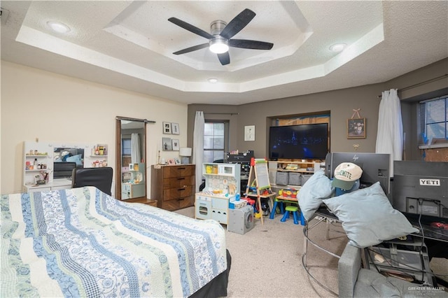 carpeted bedroom featuring a raised ceiling, a textured ceiling, and ceiling fan