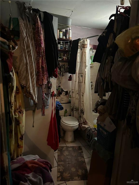 bathroom with tile patterned floors, toilet, and shower / bathtub combination with curtain