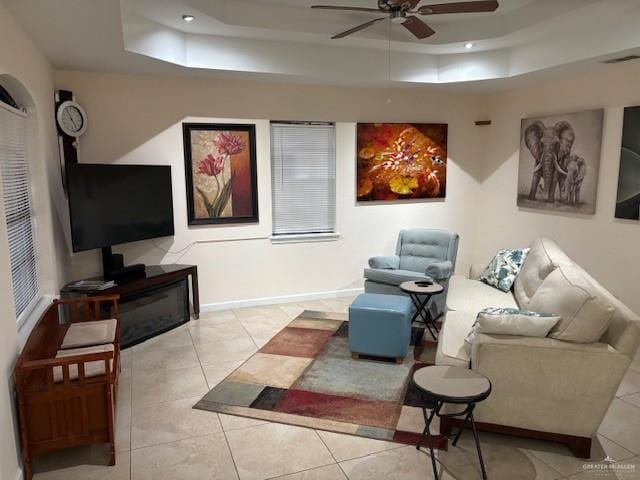 tiled living room featuring a raised ceiling and ceiling fan