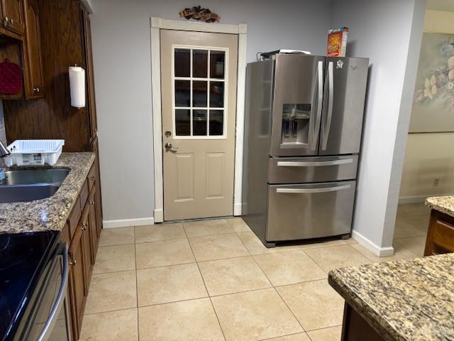 kitchen with light stone counters, stainless steel fridge with ice dispenser, sink, and light tile patterned flooring