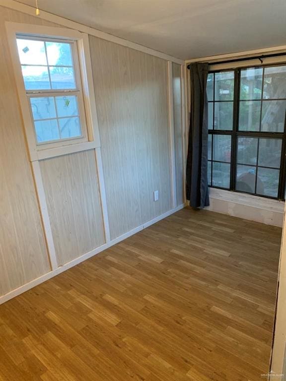 empty room featuring wood-type flooring and wooden walls