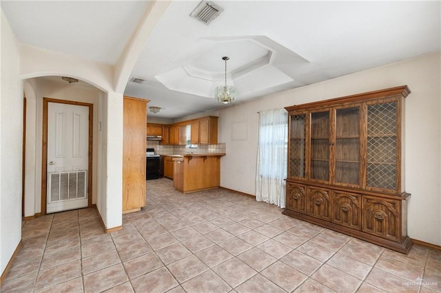 kitchen with stainless steel range with electric cooktop, hanging light fixtures, decorative backsplash, light tile patterned floors, and a chandelier