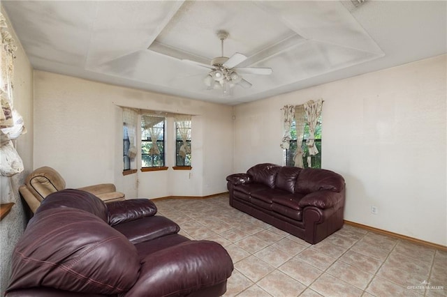 tiled living room with a tray ceiling and ceiling fan