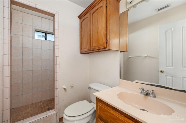 bathroom with vanity, toilet, and tiled shower