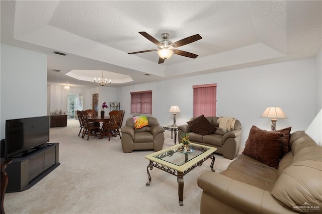 carpeted living room with a tray ceiling, ceiling fan with notable chandelier, and a textured ceiling