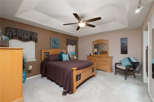 bedroom with carpet floors, a textured ceiling, and a tray ceiling