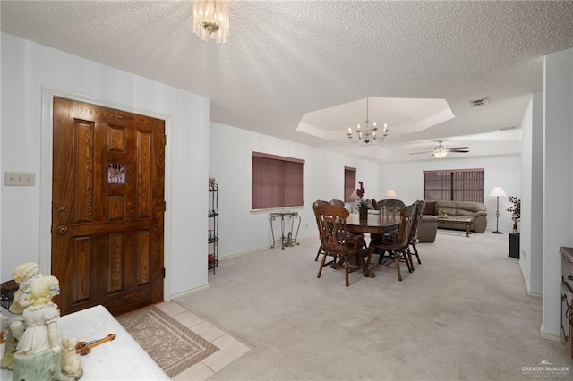 carpeted dining room with a raised ceiling, ceiling fan with notable chandelier, and a textured ceiling