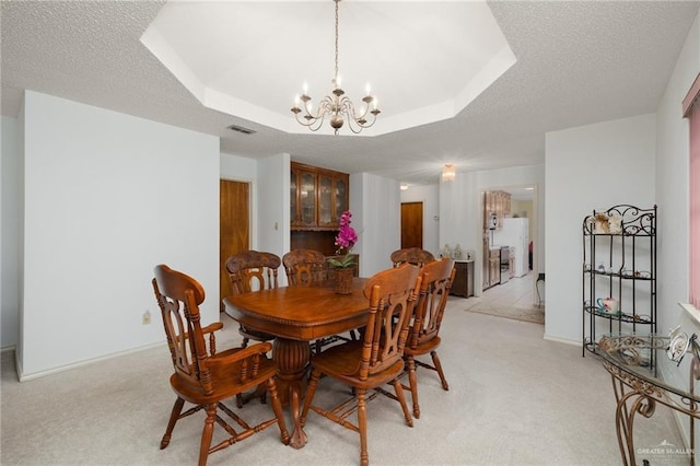 carpeted dining room featuring a raised ceiling, an inviting chandelier, and a textured ceiling