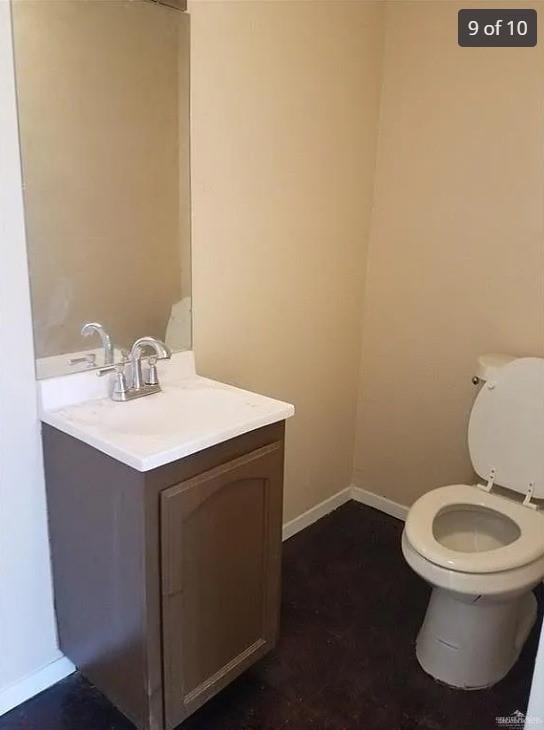 bathroom featuring toilet, vanity, and baseboards