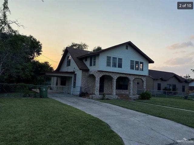 view of front of home featuring a yard, stone siding, and fence