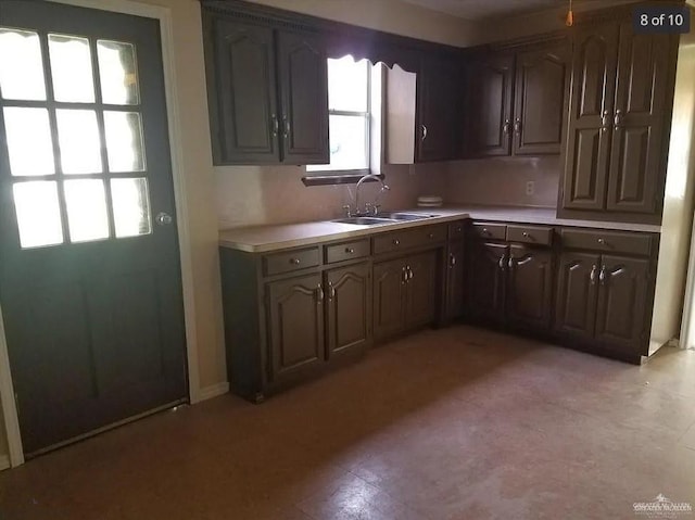 kitchen featuring light countertops, dark brown cabinets, and a sink