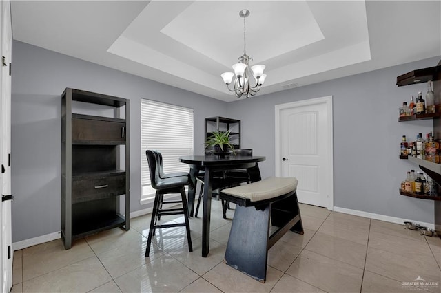 dining space with light tile patterned floors, an inviting chandelier, a raised ceiling, and bar