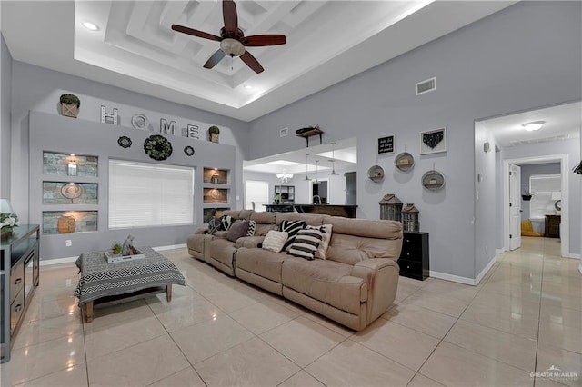 living room with a towering ceiling, light tile patterned floors, and ceiling fan with notable chandelier