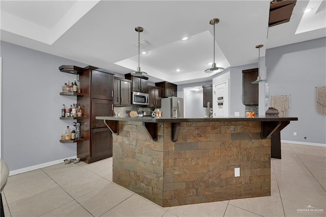 kitchen with a breakfast bar, appliances with stainless steel finishes, dark brown cabinetry, and light tile patterned floors