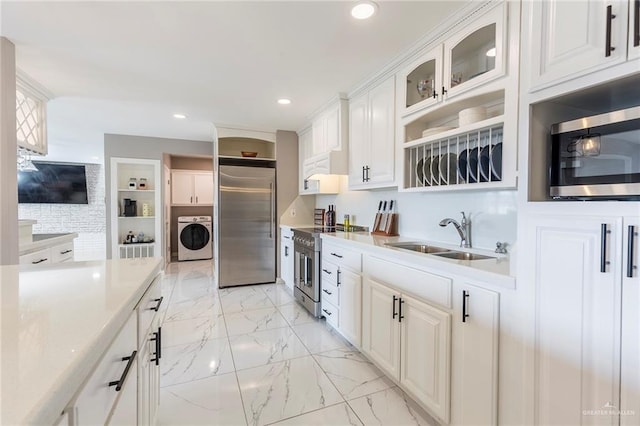 kitchen with washer and clothes dryer, white cabinetry, sink, and high end appliances