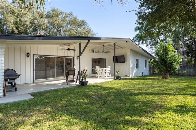 rear view of house featuring ceiling fan, a patio area, and a lawn