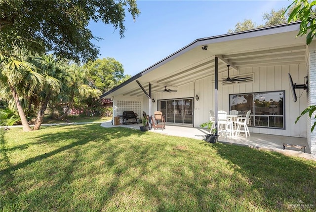 rear view of property featuring ceiling fan, a patio area, and a yard