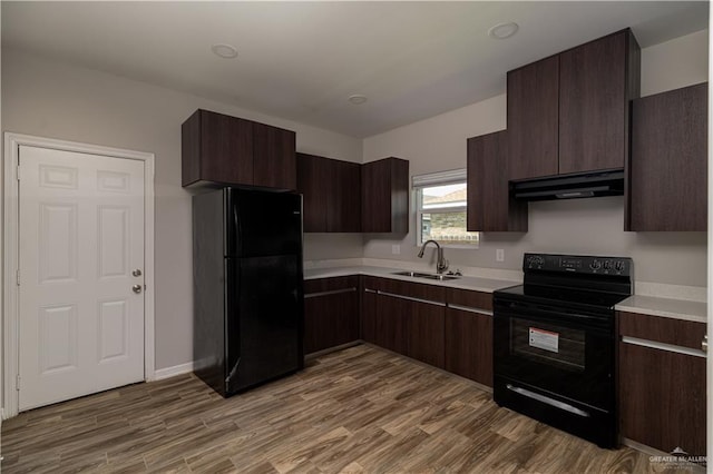 kitchen featuring hardwood / wood-style flooring, dark brown cabinetry, sink, and black appliances