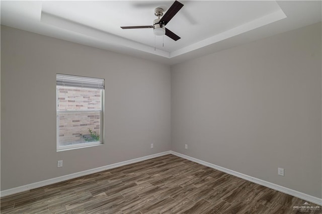 unfurnished room featuring ceiling fan, wood-type flooring, and a tray ceiling