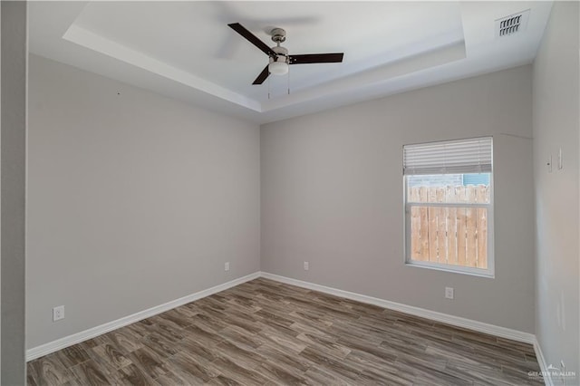 unfurnished room featuring ceiling fan, a raised ceiling, and hardwood / wood-style floors