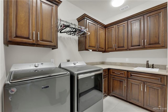 laundry room featuring washer and clothes dryer, sink, light tile patterned flooring, and cabinets