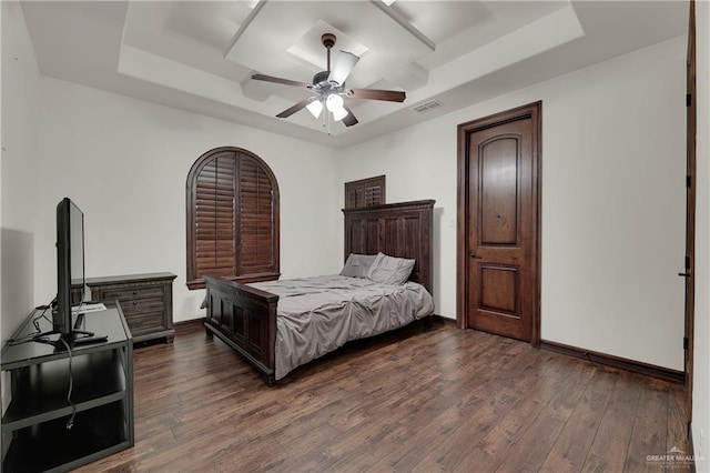 bedroom with dark hardwood / wood-style flooring, a raised ceiling, and ceiling fan