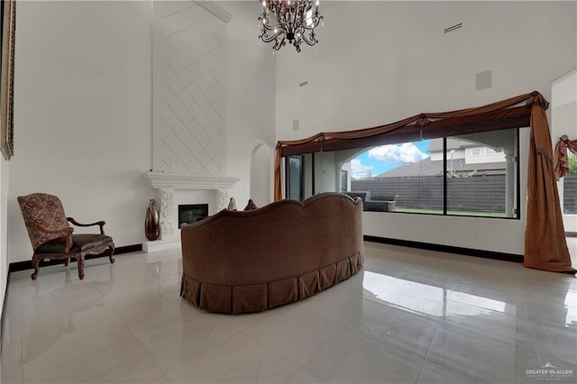 living room with a fireplace, light tile patterned floors, a towering ceiling, and a chandelier