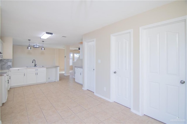 kitchen with light tile patterned floors, sink, white cabinets, decorative light fixtures, and kitchen peninsula