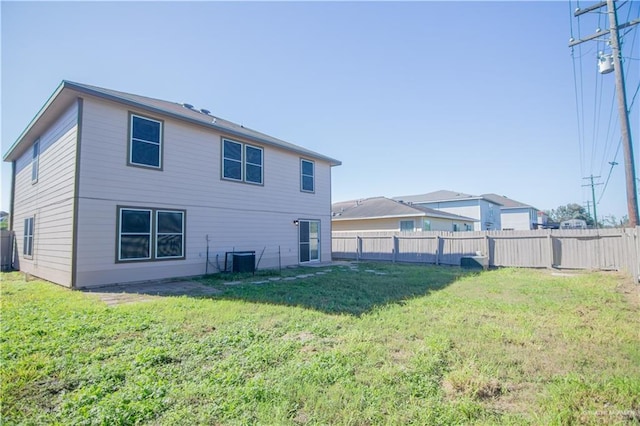 rear view of property with a lawn and central air condition unit