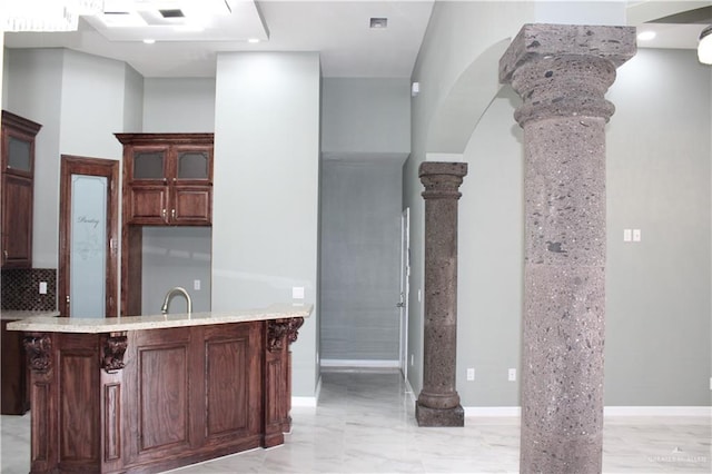 kitchen with decorative backsplash, sink, ornate columns, and kitchen peninsula