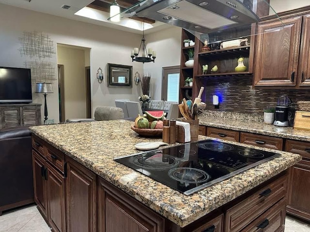 kitchen featuring black electric stovetop, light stone countertops, dark brown cabinetry, and tasteful backsplash