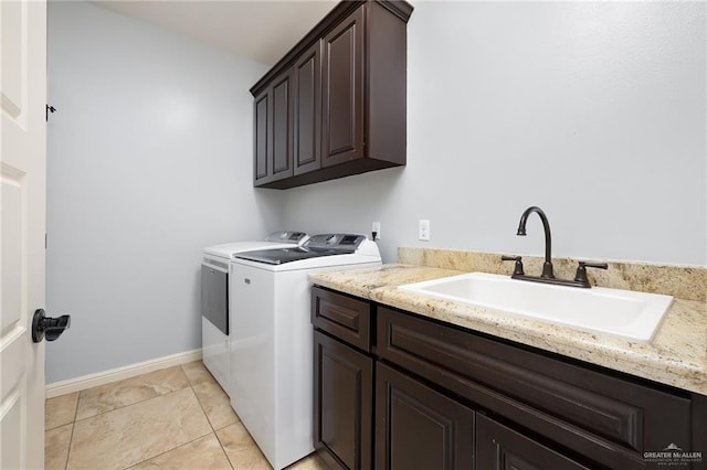 clothes washing area with washing machine and dryer, cabinet space, and baseboards