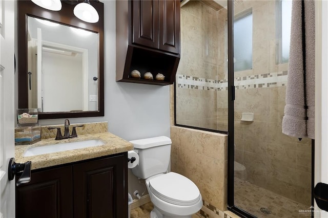full bathroom featuring a stall shower, toilet, and vanity