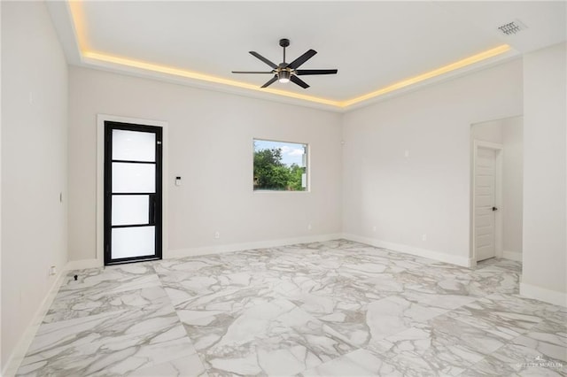 spare room featuring a tray ceiling and ceiling fan