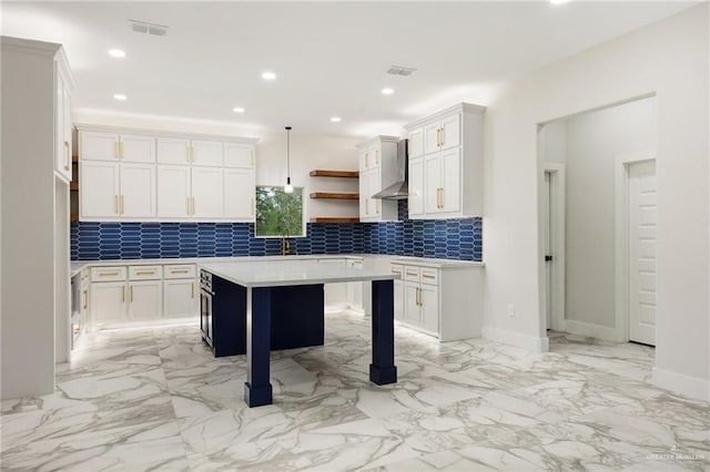 kitchen featuring backsplash, white cabinets, hanging light fixtures, and wall chimney range hood