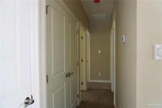 hallway with baseboards, visible vents, and dark wood-style flooring