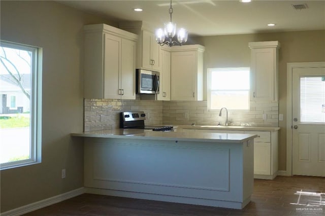 kitchen featuring stainless steel appliances, tasteful backsplash, a peninsula, and light countertops