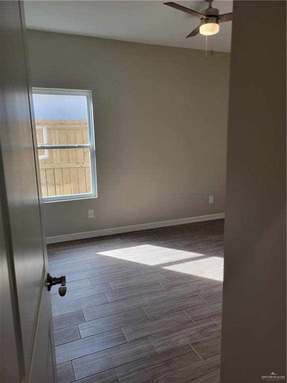 unfurnished room featuring wood tiled floor, baseboards, and a ceiling fan