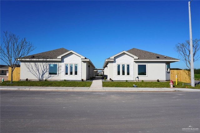 view of front of home with roof with shingles and fence