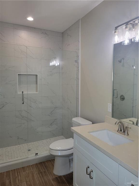 bathroom with toilet, a stall shower, vanity, and wood finish floors