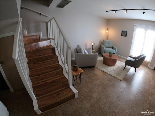 stairway featuring track lighting and tile patterned flooring