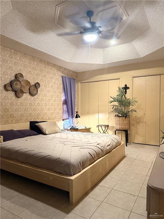 2612 Ashley Dr, Pharr, TX 78577 - bedroom featuring multiple closets, wallpapered walls, light tile patterned floors, and a ceiling fan